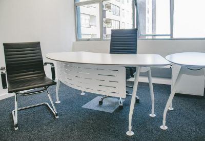 Private office suite featuring a modern white desk and two black leather executive chairs.