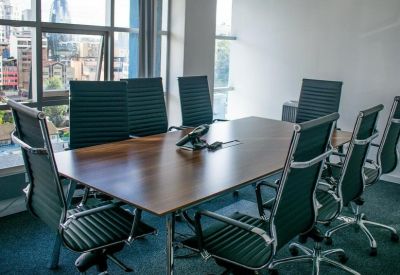 Professional meeting room with a wooden table, ergonomic chairs, and large windows with city views.