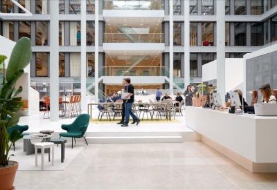 Modern multi-story building atrium with a sleek white reception desk and greenery.