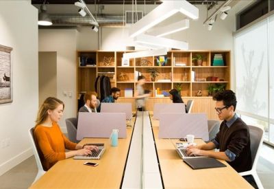 Shared workspace featuring long wooden desks and unique geometric overhead lighting.