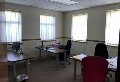 Private internal office with two desks and vertical window blinds.