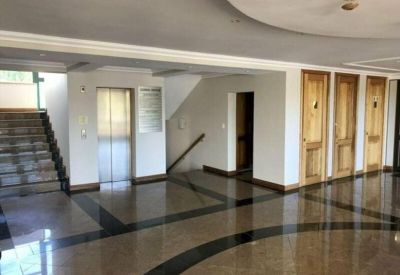 Spacious lobby with polished stone floors, an elevator, and wooden doors.