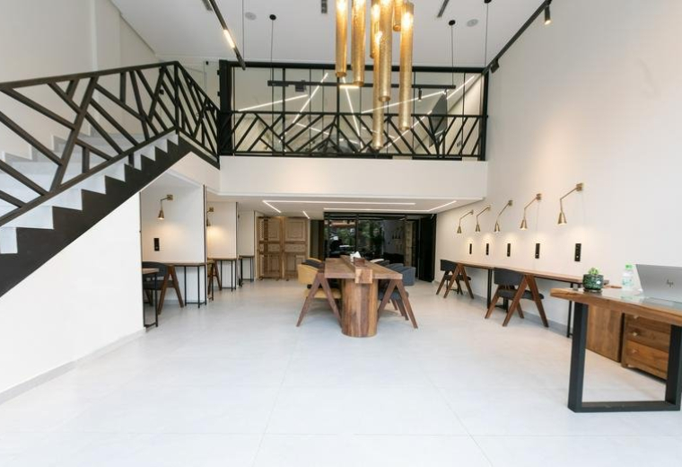 Spacious communal coworking area at Khaymat El Izdihar, Oasis 2, Sanawbar, Marrakech with wood tables and mezzanine.