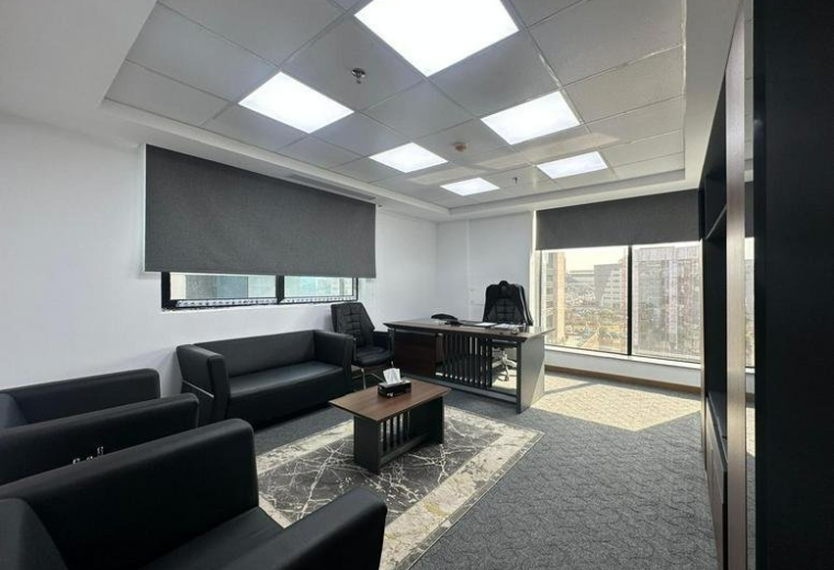 Private executive office with black leather sofa seating and a dark wood desk.
