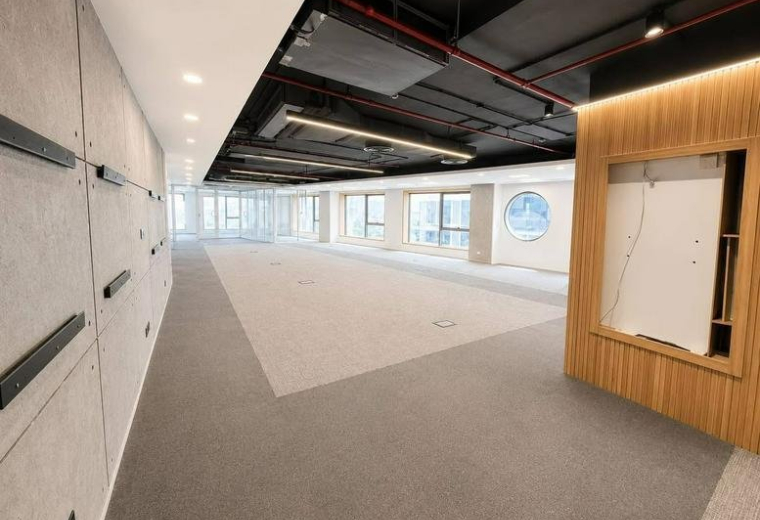 Spacious open-plan workspace at التسعين الجنوبي, New Cairo with industrial ceilings and concrete feature walls.
