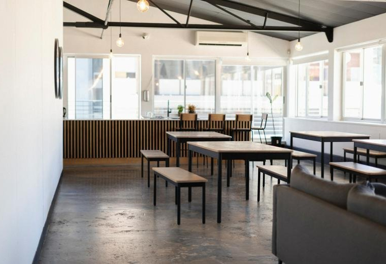 Spacious communal dining area at 79, Loop Street with wooden tables and black industrial ceiling beams.