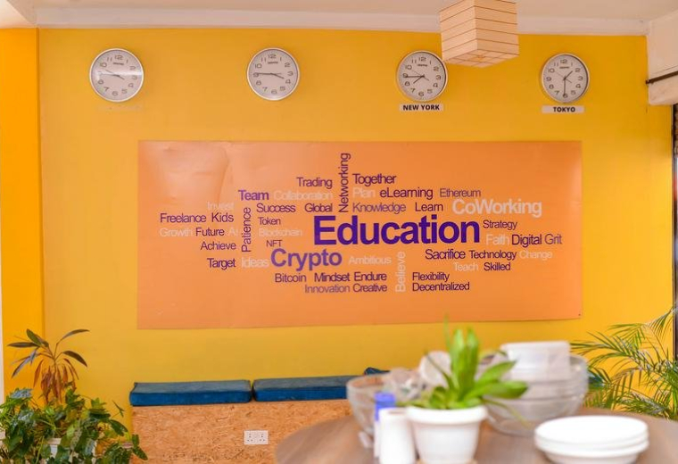Reception area at Cooper House 2 with a yellow feature wall, world clocks, and educational word cloud art.