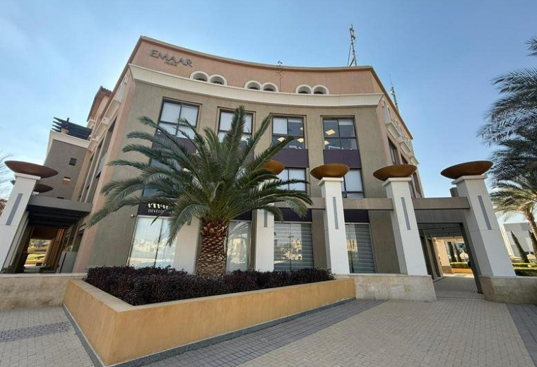 Exterior view of the curved facade at mivida Business Park with a central palm tree.
