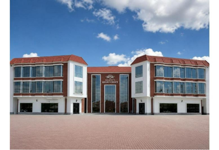 Exterior facade of the brick and white Rege, Norh 90th New Cairo building under a bright blue sky.