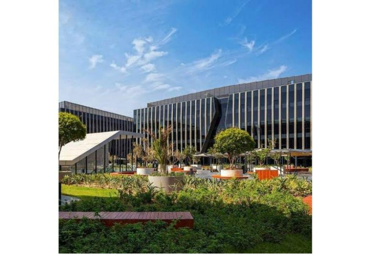 Exterior view of the modern glass-facade building at Sodic EDNC with landscaped gardens.