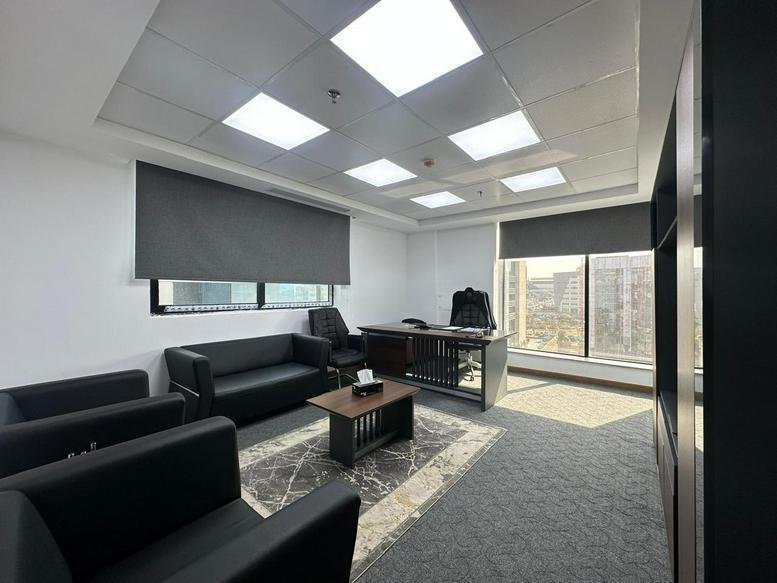 Private executive office with black leather sofa seating and a dark wood desk.