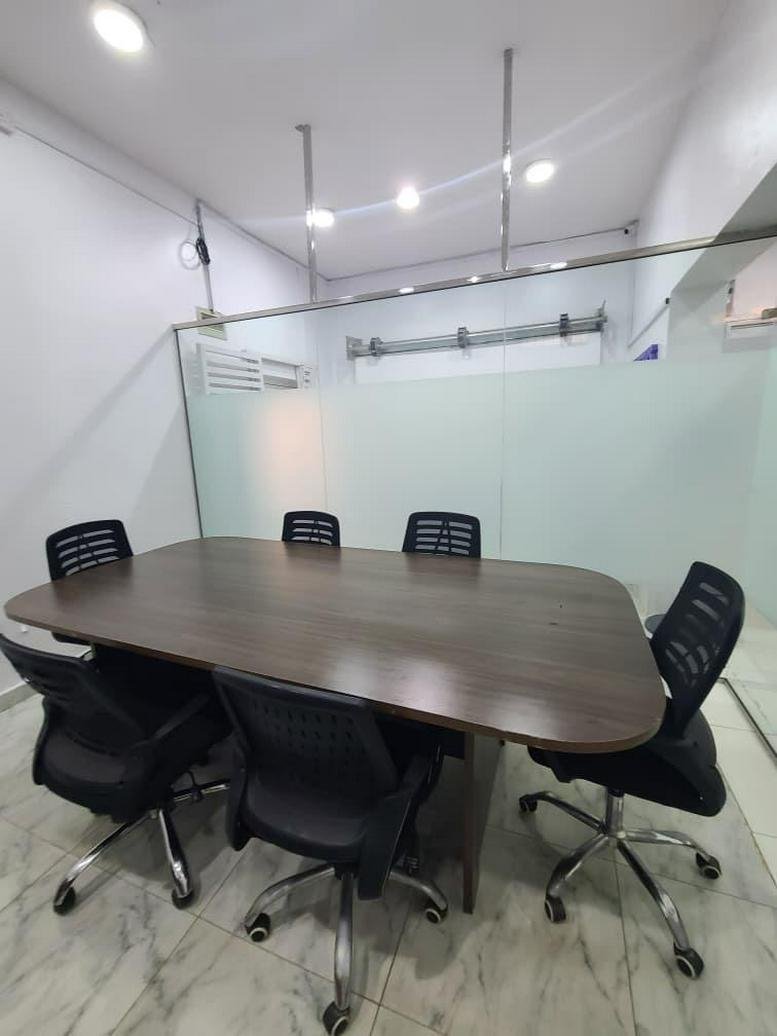 Meeting room at 1, Freedom Estate Drive with a large wood-finish table and six black mesh chairs.