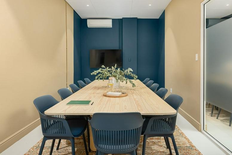 Meeting room with long light-wood table, teal chairs, and teal feature walls at 129, Bree Street.