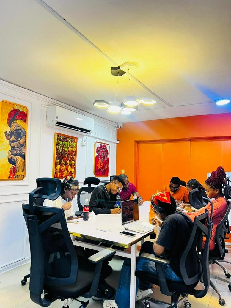 Team meeting at a large white table in a vibrant office at 29, 204 Road, Festac Town.