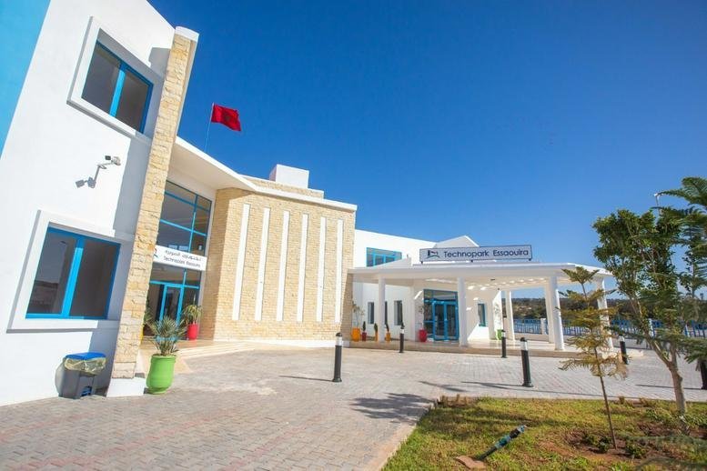 Exterior view of the modern white and stone Technopark Essaouira building under a clear blue sky.