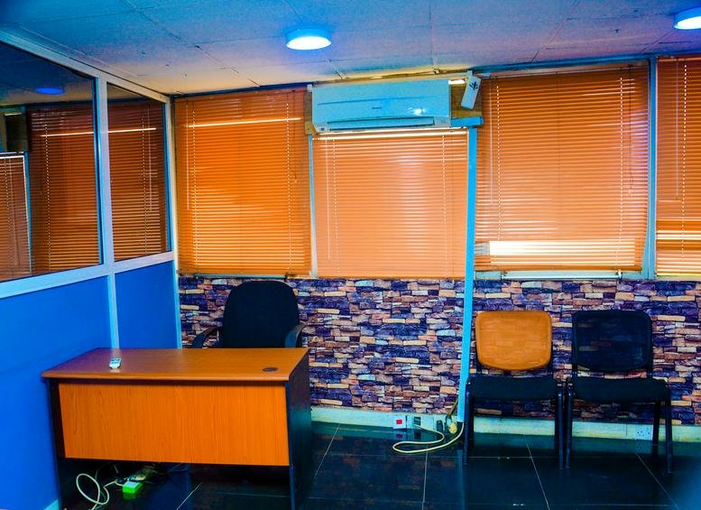 Private office at 9th Floor, Cocoa House, Dugbe with wooden desk, blue accents, and orange window blinds.