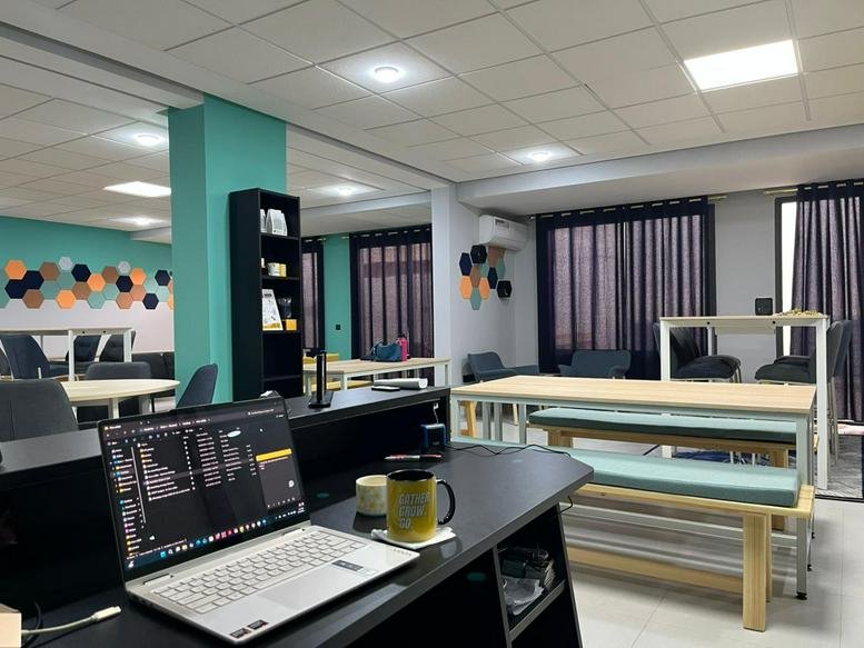 Modern open-plan workspace with teal accent pillars and wooden benches.
