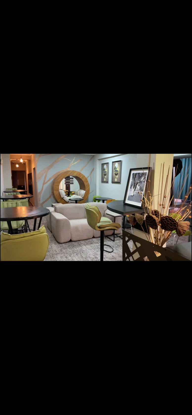 Spacious communal lounge at Bemud,, featuring a circular wood-framed reading nook and green velvet chairs.