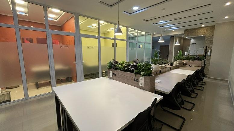 Spacious interior of Centre Commercial Mohammadia Mall coworking area with long white desks and glass partitions.