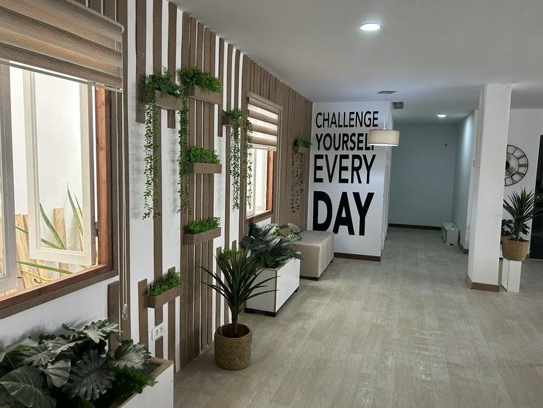 Bright reception area at 007 Rue de L'or with vertical wood slats, potted plants, and motivational wall text.