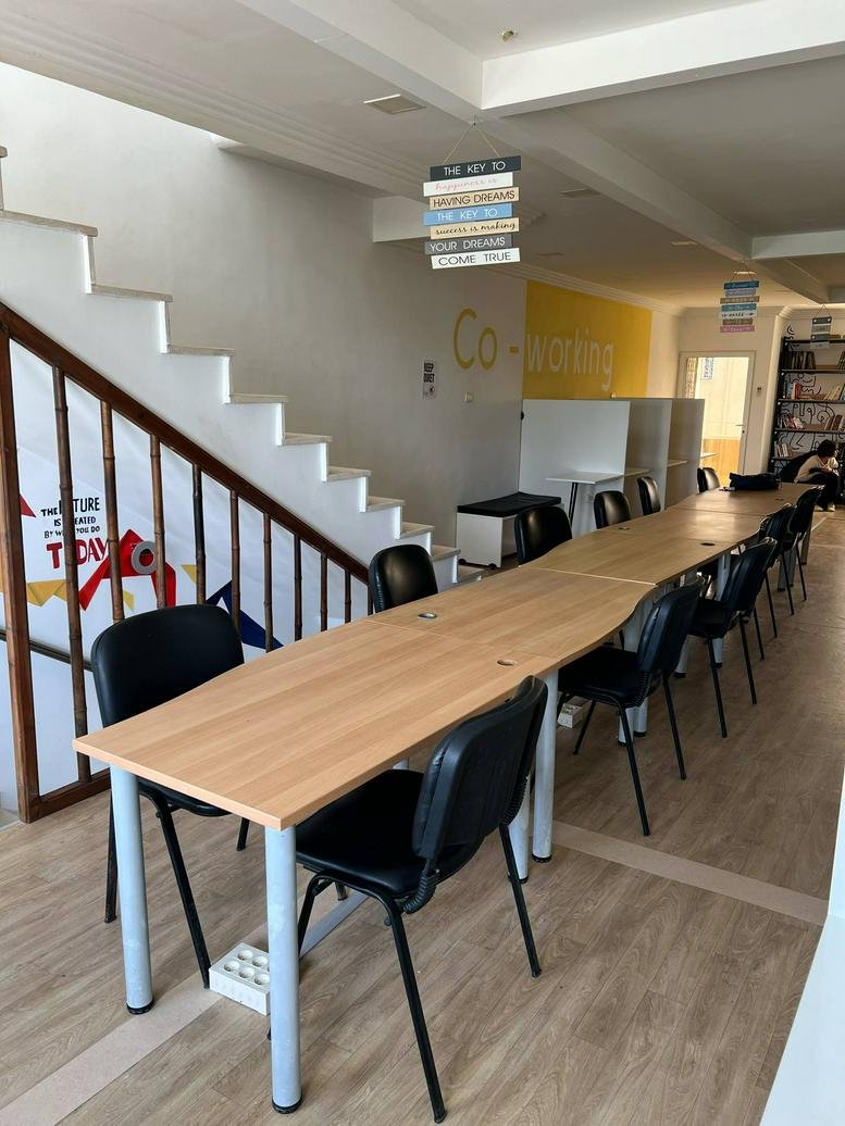 Coworking space at 12 Rue de la Municipalité featuring long wooden desks and a modern staircase.