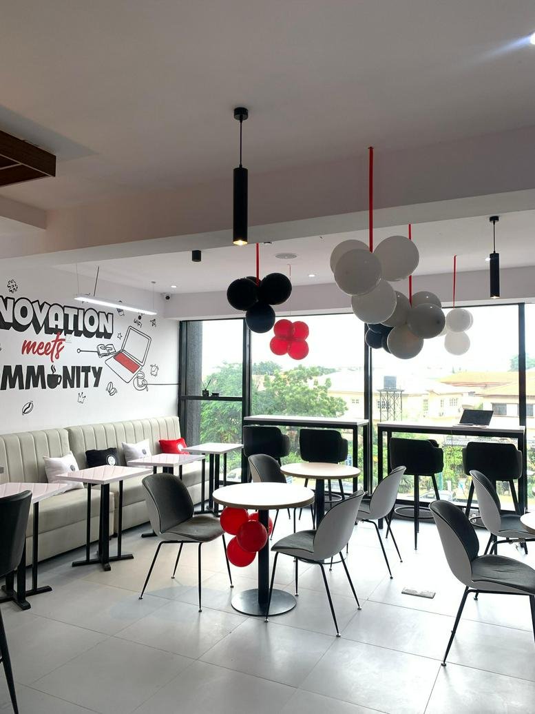 Modern communal cafe area at 21, Admiralty Way, Lagos with grey chairs, round tables, and balloon decorations.