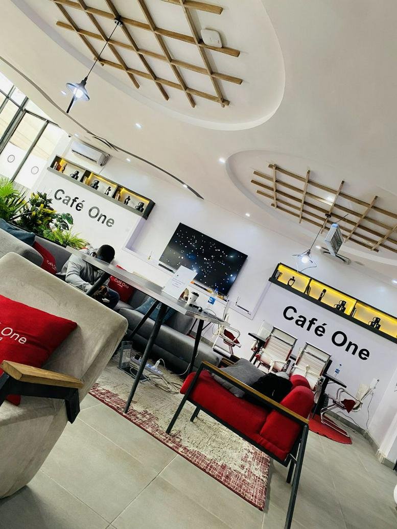 Spacious communal lounge at Café One, 28 Okpara Avenue, Enugu, Nigeria with modern seating and decorative wood ceilings.