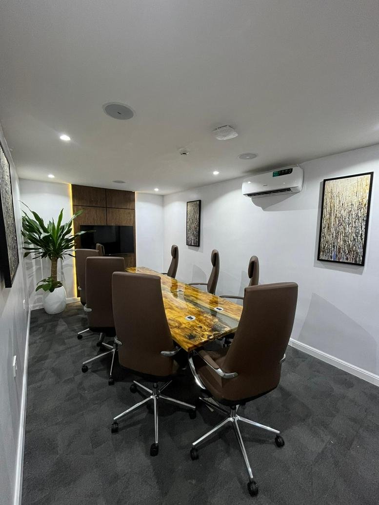 Meeting room at 300 Adeola Odeku Street featuring a unique live-edge wood conference table and brown leather chairs.
