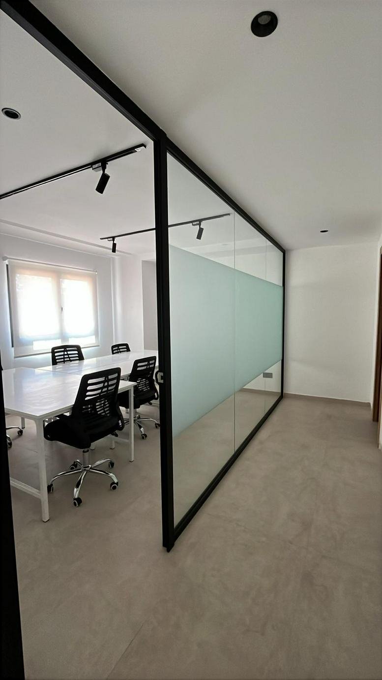 Meeting room at Imourane Building featuring a long white table and glass partitions with frosted privacy bands.