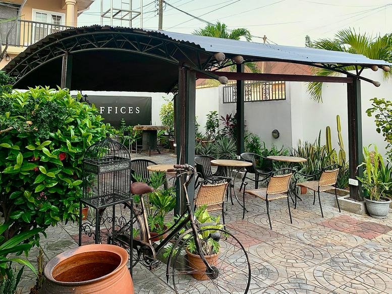 Outdoor patio at L'Atelier, Osae Link, East Legon, Accra, Ghana featuring a black canopy and cafe seating.