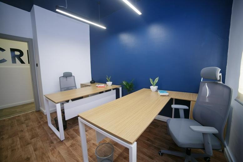 Bright office at Rue Ibn Hilel, Menzah 5 featuring wooden desks and a deep blue feature wall.
