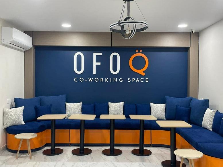 Lounge area with blue tiered seating and orange accents at Ofoq Co-Working Space, 965 Omar Ibn El-Khattab St.