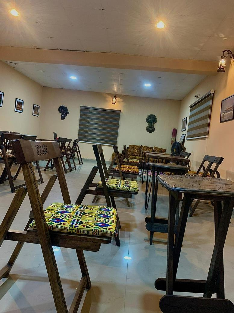 Cafe-style seating at Nsibidi Sanctuary with wooden folding chairs and vibrant patterned cushions.