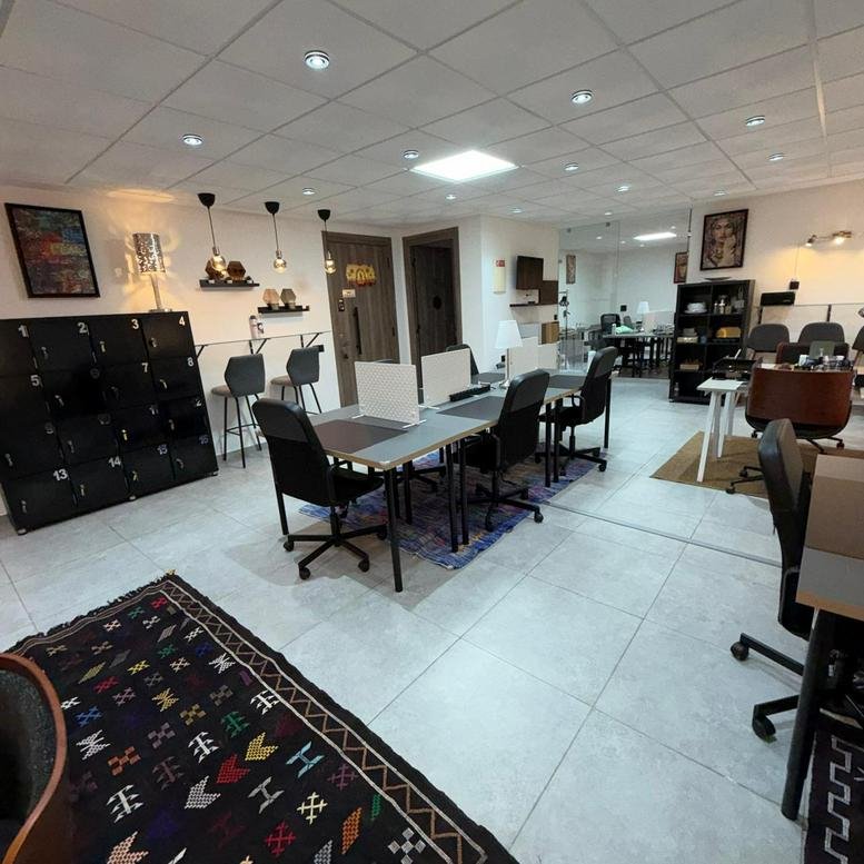 Spacious coworking space at Cowork'skech Centre d'Affaires Eden Parc with desks and decorative rugs.
