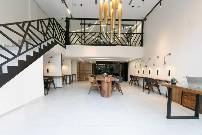 Spacious communal coworking area at Khaymat El Izdihar, Oasis 2, Sanawbar, Marrakech with wood tables and mezzanine.