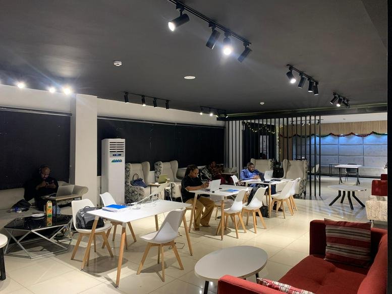 Spacious communal lounge at Sterling Bank Plaza, Mohammadu Buhari Way, featuring white cafe tables and red sofas.