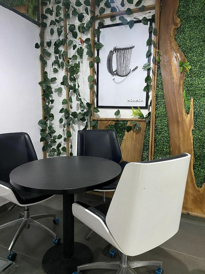 Small round cafe table with black and white chairs against a feature wall with climbing vines and wood accents.