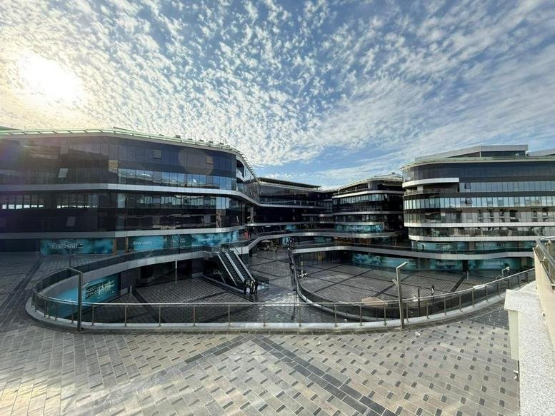 Exterior view of the modern glass-facade building at Enawallks, New Cairo with an open courtyard.