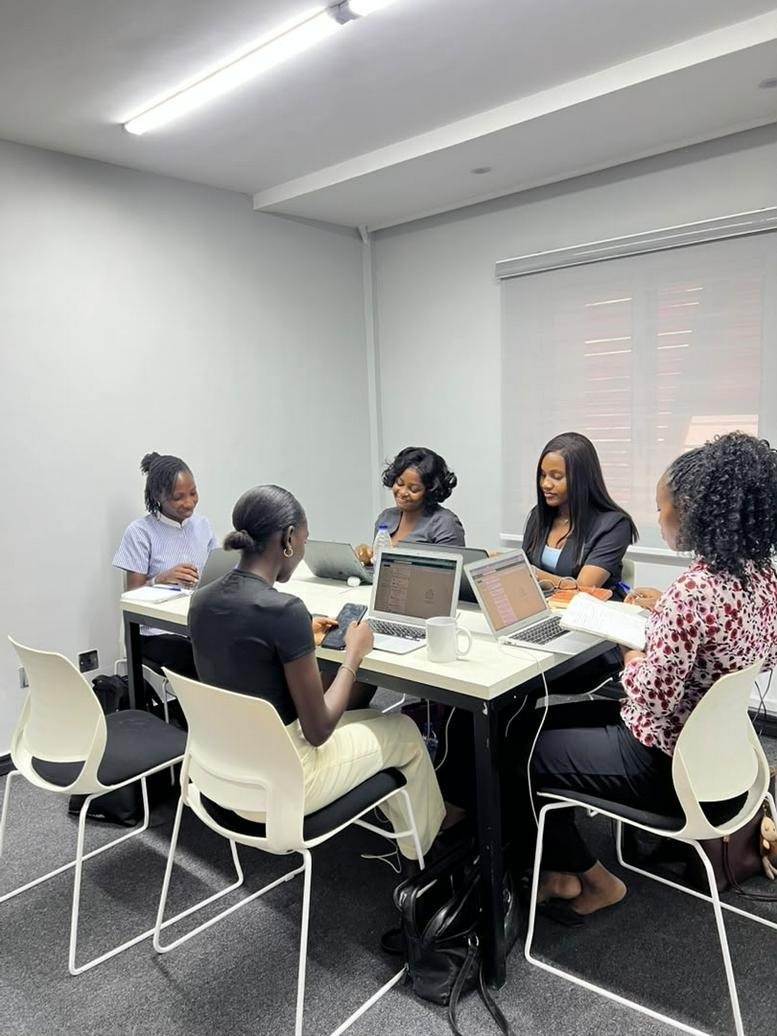 Team of five people working around a large white meeting table at Oba Akinloye Close.