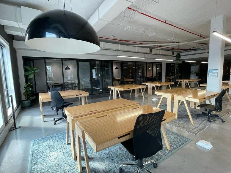 Spacious open-plan workspace at The Old Foundry with light wood desks and large black pendant lights.