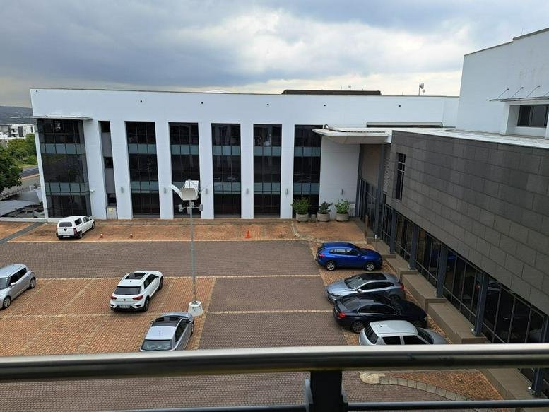 Exterior view of the white modern office building at 345 Rivonia Road with parking area.