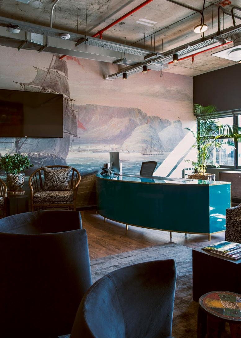 Reception area with teal desk and mural resembling a coastal landscape.