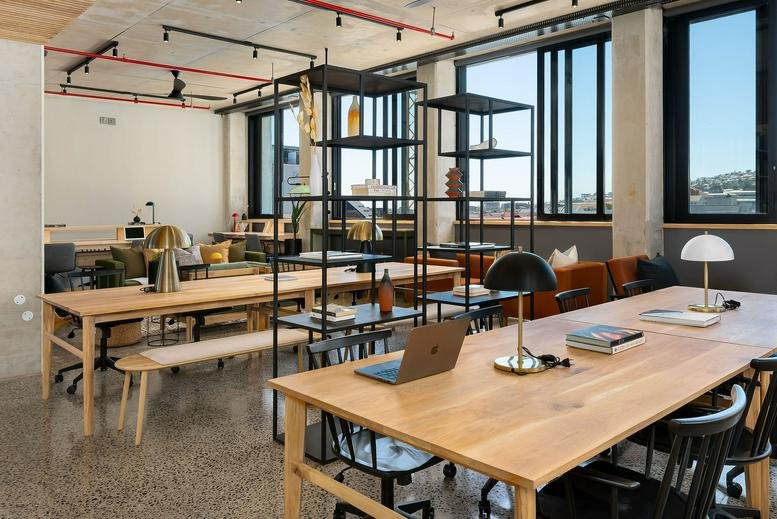 Bright coworking space at 84 Harrington Street, 5th Floor with long wooden desks and city views.