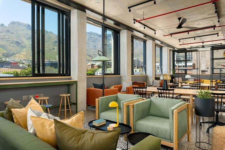 Lounge area with light green armchairs and large windows showing mountain views.