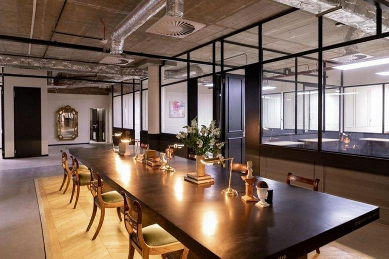 Open-plan workspace with a large communal table and exposed ceiling design.