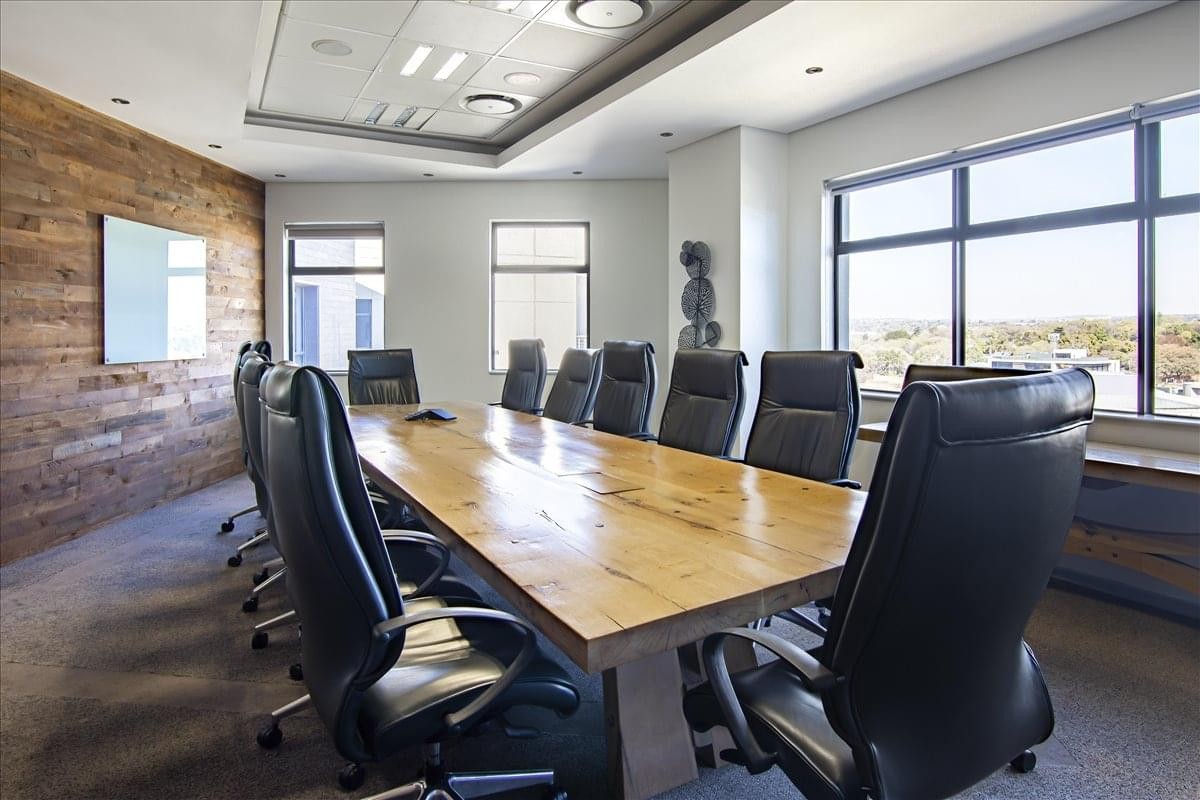 Professional boardroom at Bloukrans Building featuring a long wooden table and black leather chairs.