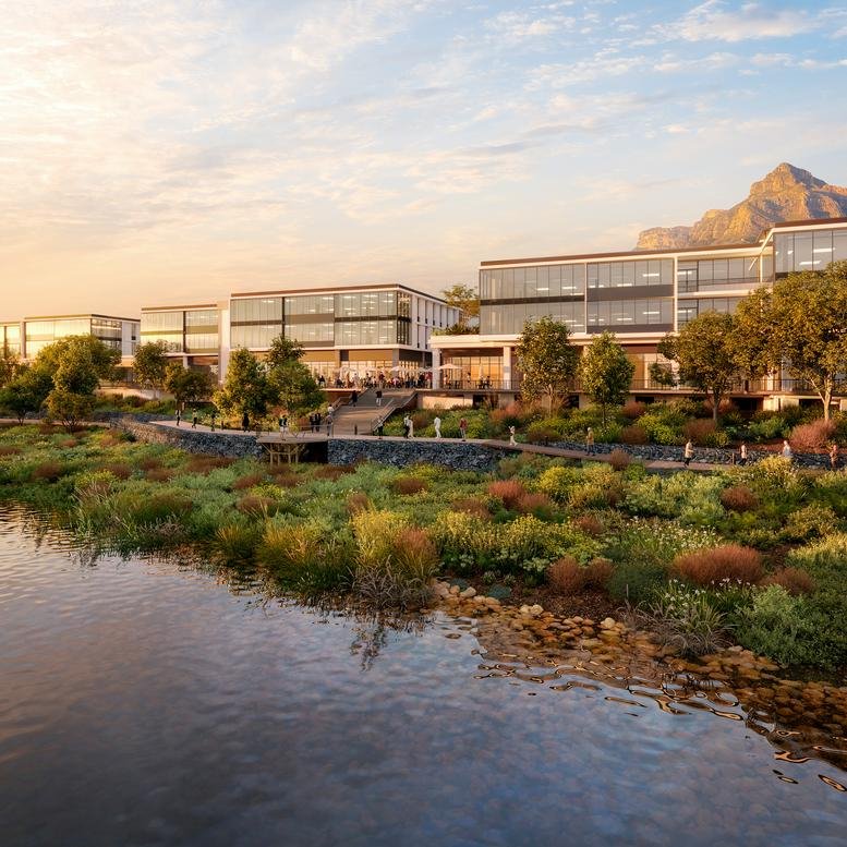 Modern waterfront exterior of Building 4 at Riverlands Mall with mountains in the background at sunset.