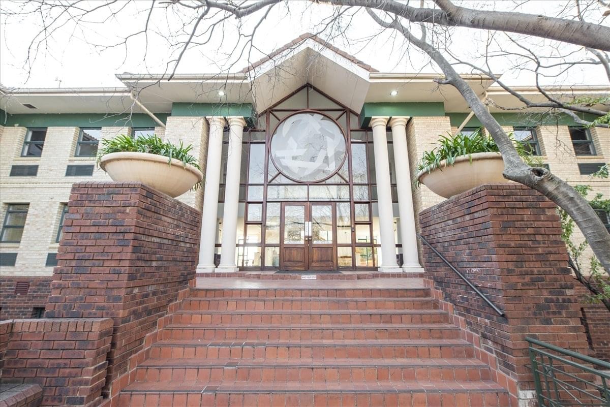 Grand brick entrance of the 6 Kikuyu Road building with large planters and glass doors.
