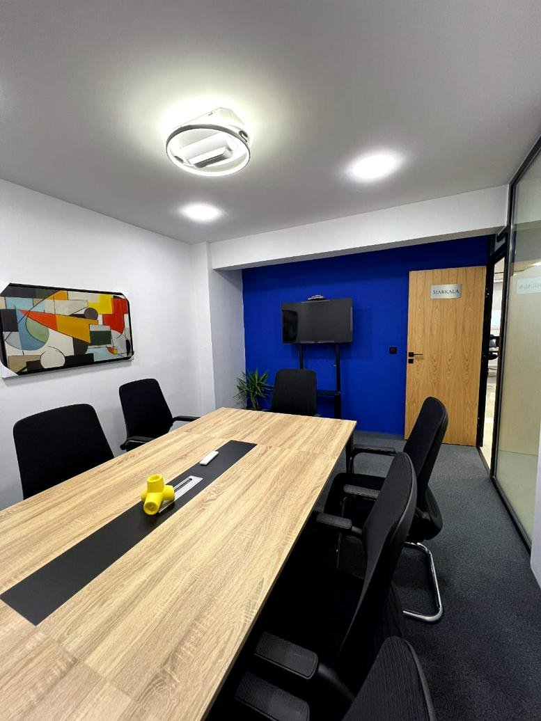 Professional meeting room with a light wood table, black chairs, and a vibrant abstract wall art piece.