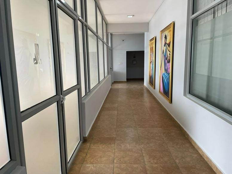 Brightly lit hallway at Ambassador Albert Osakwe House with tiled floors and framed artwork.